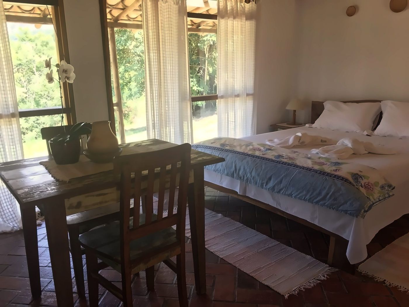 Quarto com cortinas leves e janelas para a mata