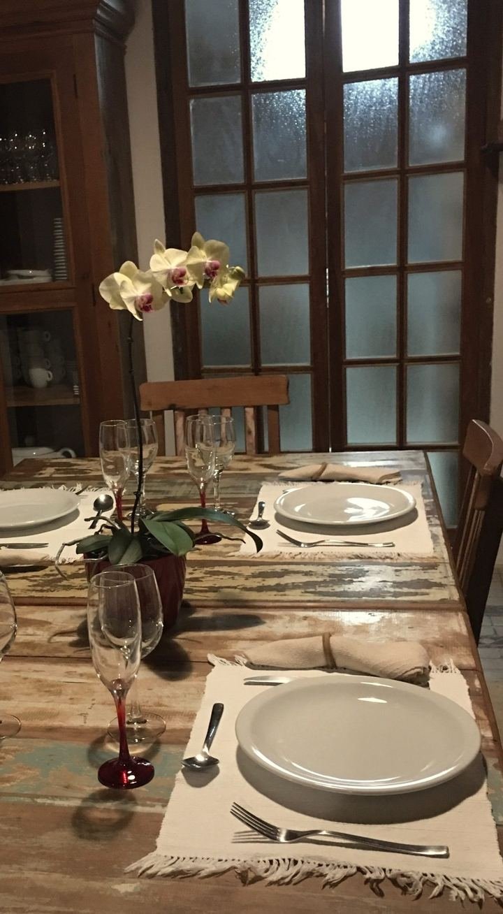 Mesa de madeira posta com orquídea, pratos e taças